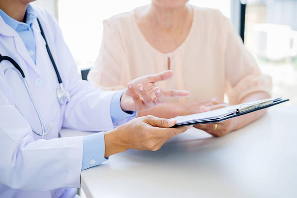 ασθενής, ακούγοντας με προσήλωση σε ένα αρσενικό ο γιατρός εξηγεί τα συμπτώματα των ασθενών ή μια ερώτηση, όπως συζητούν μαζί χαρτιά σε διαβούλευση - Φωτογραφία, εικόνα