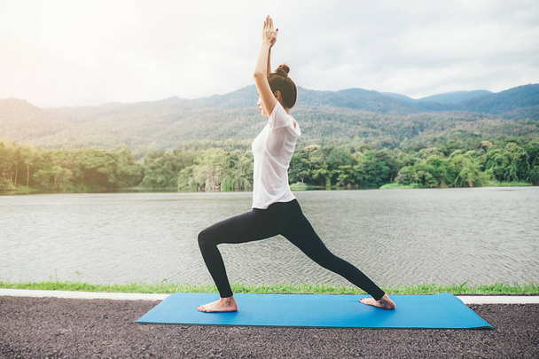 Yoga-Konzept. junge Frau meditiert während sie Yoga im Park praktiziert. Ruhe und Entspannung, weibliches Glück. verschwommener Garten auf dem Hintergrund - Foto, Bild