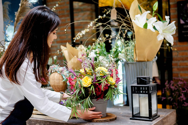 Веселий чарівний молодий власник магазину квітів, квітковий магазин, що стоїть і тримає квіти
 - Фото, зображення