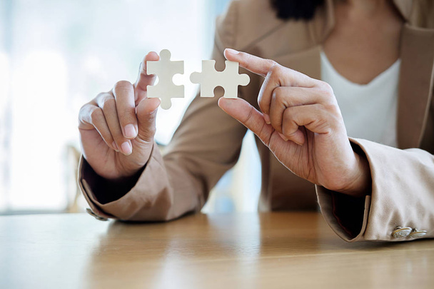 Business woman hands connecting jigsaw puzzle. Business solutions, success and strategy concept. Close up photo with selective focus. - Photo, Image