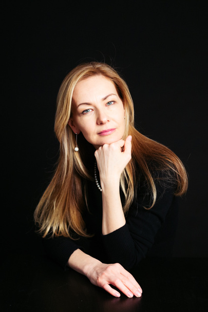 Close up studio portrait of a beautiful woman in the black dress against black background - Fotó, kép