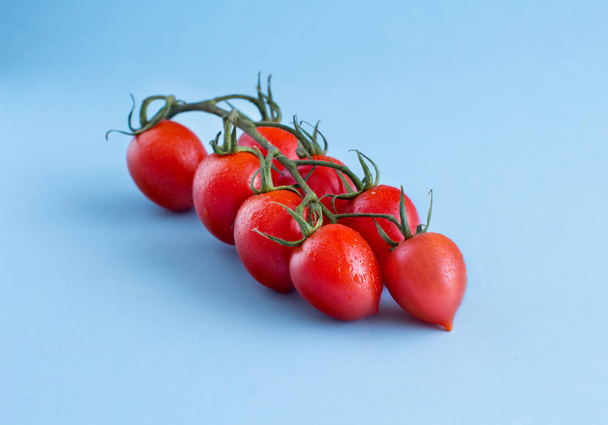 Cherry tomaten op een blauwe achtergrond close-up - Foto, afbeelding