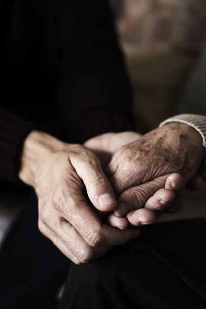 Nahaufnahme eines jungen kaukasischen Mannes, der die Hand einer alten kaukasischen Frau liebevoll hält - Foto, Bild