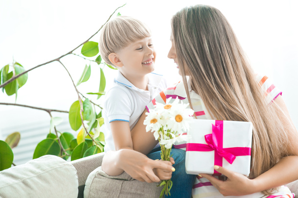 Cute little child congratulates his mother with mothers day. Adorable boy with is mom holding a present for 8th of march or birthday. Happy family celebrating - Photo, Image