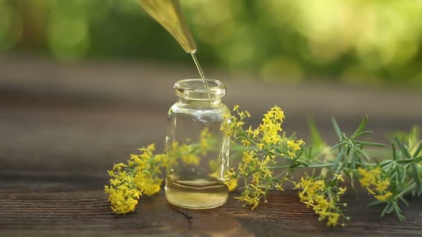 Ätherisches Öl aus gelbem Bettstroh in schöner Flasche auf dem Tisch - Filmmaterial, Video