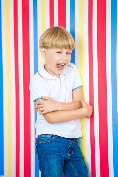 Cute child close up portrait on colorful background. Adorable little boy standing near to the wall. - Foto, Imagen