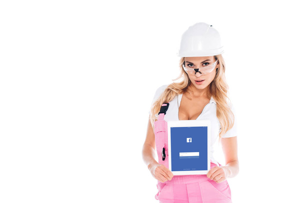 mulher útil em uniforme rosa e óculos segurando tablet digital com aplicativo facebook na tela isolada no branco
 - Foto, Imagem