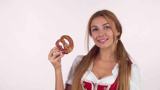 Sexy mujer bávara lamiéndose los labios, mirando delicioso pretzel
 - Foto, Imagen