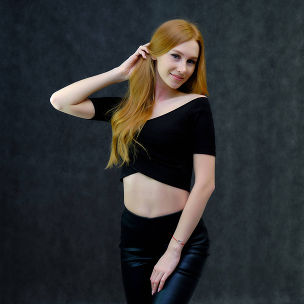 Concept portrait of a cute beautiful red-haired girl talking on a gray background in the studio standing in front of the camera. It shows different emotions in different poses. - Фото, зображення