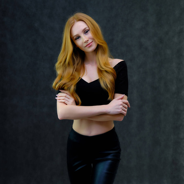 Concept portrait of a cute beautiful red-haired girl talking on a gray background in the studio standing in front of the camera. It shows different emotions in different poses. - Fotoğraf, Görsel