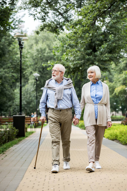 счастливая улыбающаяся пожилая пара, гуляющая в парке
 - Фото, изображение