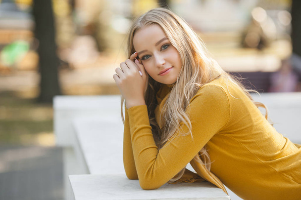 Closeup portrait of young attractive woman outdoors with copy space. Beautiful blond girl model. Cheerful lady on neutral background spring, fall, autumn. - Foto, Imagen