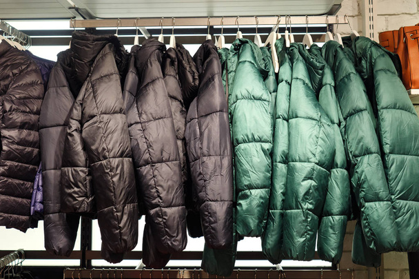 Stojan s trendy teplé kabáty ze zelené a černé barvy v obchodě s oděvy - Fotografie, Obrázek