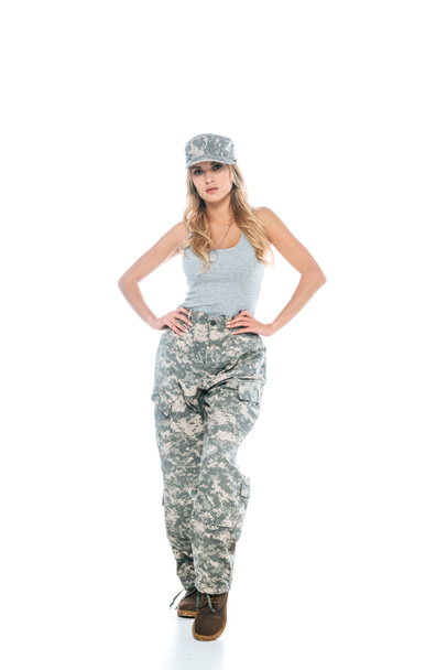 militarywoman in grey t-shirt, camouflage pants and cap on white background - Фото, изображение