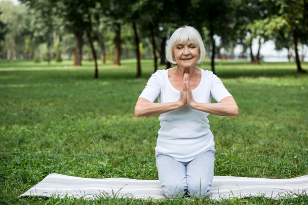 старша жінка на йога мат в медитації Сухасана сидить позу зі складеними руками
 - Фото, зображення