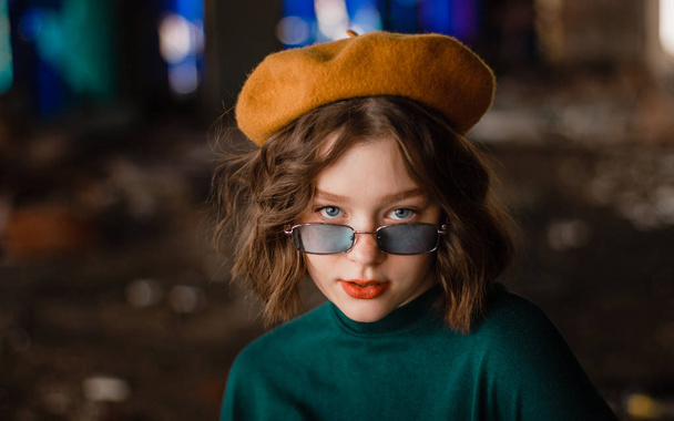 schönes lockiges junges Mädchen mit blauer Sonnenbrille, das in die Kamera blickt - Foto, Bild