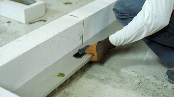 checking evenness of aerated concrete wall with spirit level - Фото, изображение