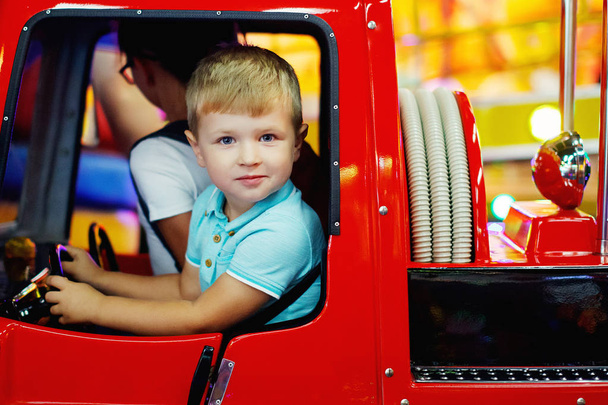 かわいい十代の少女と少年グッズ車アーケードのカルーセルに乗って遊園地のゲーム機で - 写真・画像