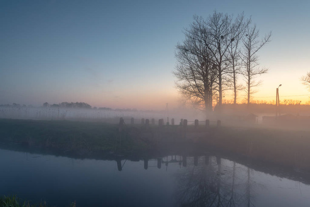Misteriosa noche de niebla en un campo cerca del río al atardecer. Pueblo de Karwia en Polonia
. - Foto, Imagen