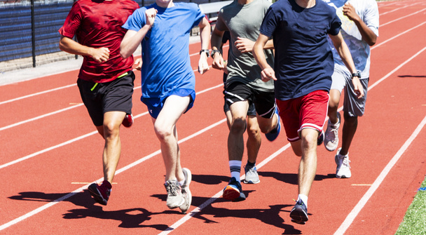 Una squadra di liceali maschili corre veloce in un gruppo su una pista durante le prove sul campo
.  - Foto, immagini