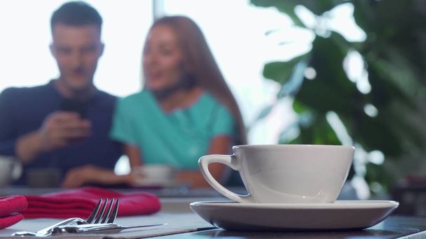 Selektiver Fokus auf eine Tasse auf dem Tisch, Paar kuschelt im Hintergrund - Foto, Bild