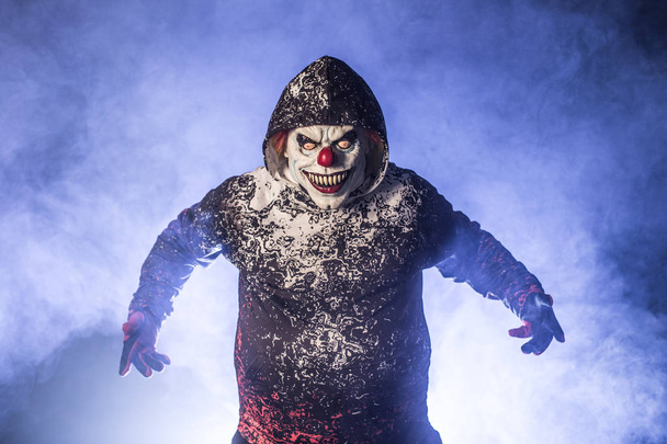 scary clown man in hood posing against misty background - Fotoğraf, Görsel