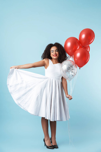 Full length of a cheerful african woman wearing dress celebrating with balloons isolated, posing - Foto, immagini