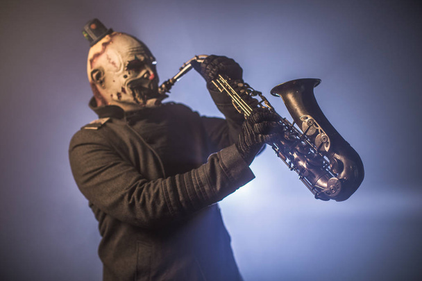 scary clown posing with saxophone against dark background - Foto, Imagen