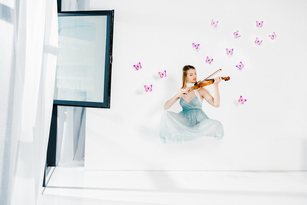 floating girl in blue dress playing violin on white background  - Foto, Bild