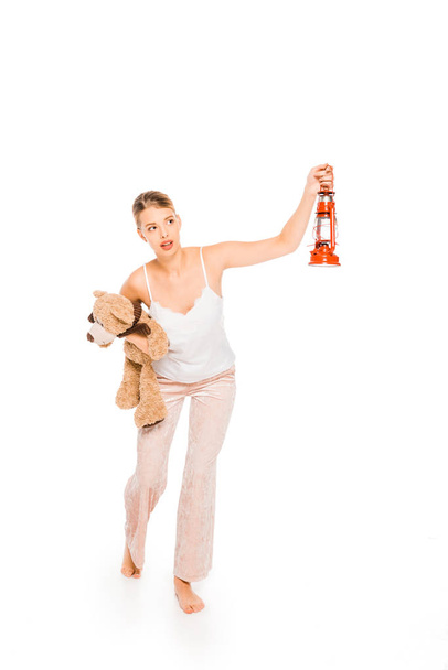 girl in pyjamas holding teddy bear and lantern isolated on white  - Фото, зображення