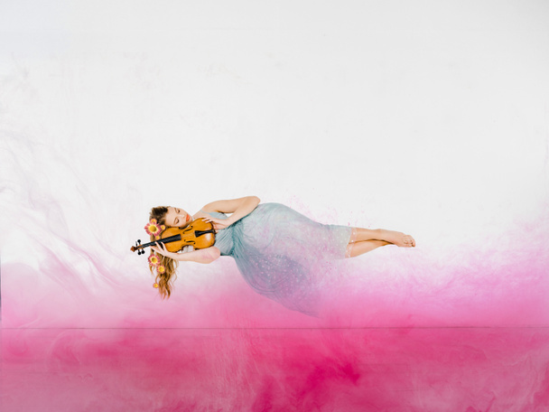 zwevende meisje in blauwe jurk slapen op viool met illustratie van de roze wolk - Foto, afbeelding