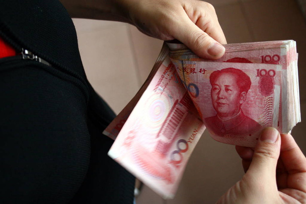 Китаянка считает банкноты юаня в городе Фуян, провинция Аньхой на востоке Китая, 17 июня 2008 г.
 - Фото, изображение