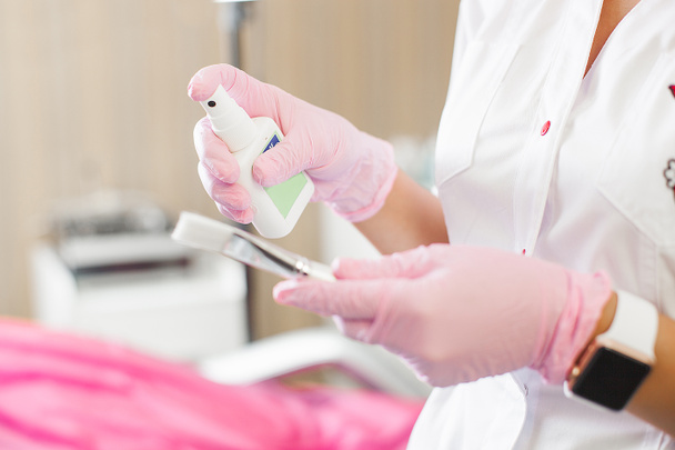 Unrecognizable doctor cleaning and disinfecting tools. Antibacterial agent in the hands close up. Cosmetologist disinfecting her hands in latex gloves before prosedure. - Photo, Image