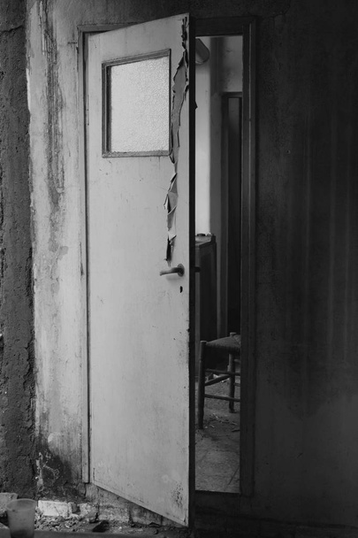 Félig nyitott nyikorgó ajtó vezet a konyhából a régi elhagyott ház belső folyosón. Fekete-fehér. - Fotó, kép