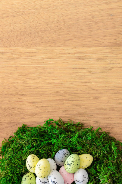 Osternest aus naturgrünem Moos und Ostereiern auf einem Holztisch - Foto, Bild