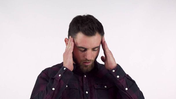 Bearded young man suffering from terrible headache, rubbing his temples - Photo, Image