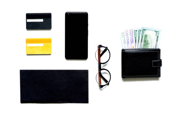 Flatlay of money in black wallet, mobile phone, glasses, bank cards, envelope on white background. Top view. business payments concept. - Foto, imagen