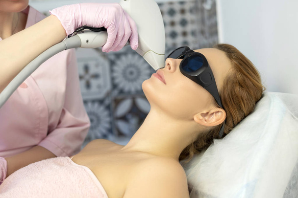 Kobieta lekarz kosmetolog usuwanie włosów z kobieta ciało klienta przy użyciu depilator laserowy. W centrum odnowy biologicznej. - Zdjęcie, obraz
