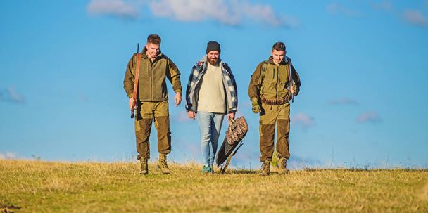 Hunters with guns walk sunny fall day. Brutal hobby. Group men hunters or gamekeepers nature background blue sky. Guys gathered for hunting. Men carry hunting rifles. Hunting as hobby and leisure - Foto, Imagem