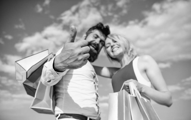 Happy couple satisfied purchases. Shopping brings positive emotions. Couple with shopping bags hugs blue sky background. Man beard and blonde girl enjoy buy clothing. Family bought excellent clothes - Photo, Image