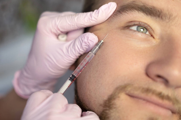Detailní krásy hlavního dělá injekce v mužský pacient tváří. Muž, aplikaci injekcí Beauty procedury pomocí výplň. Kosmetika a krása koncept obličeje injekce - Fotografie, Obrázek