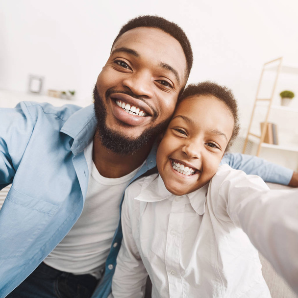 Padre afroamericano tomando selfie con su hija en casa
 - Foto, imagen