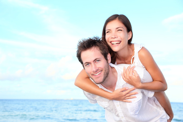 Happy beach couple piggyback - Foto, afbeelding