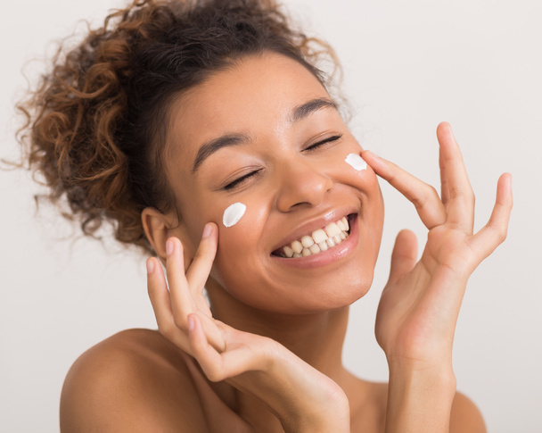 Happy african-american woman applying face cream, crop - Фото, изображение