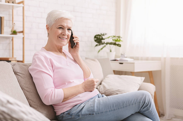 Senior woman talking on her mobile phone at home - Zdjęcie, obraz