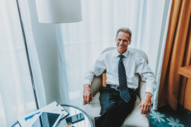Happy mature businessman smiling while posing in the armchair - Fotó, kép