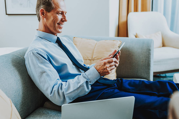 Cheerful adult man using modern tablet and smiling - Foto, Bild
