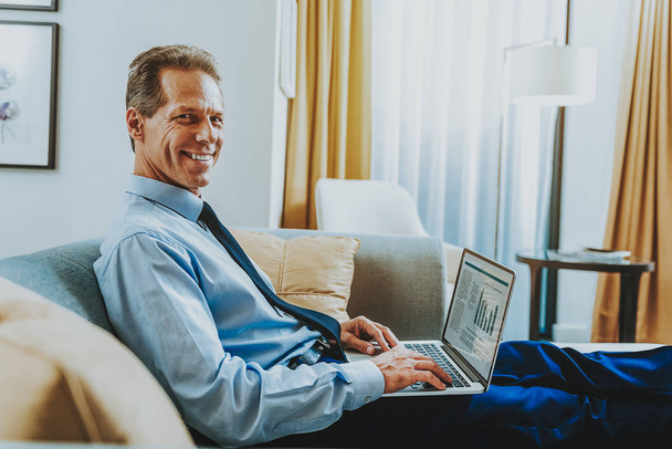 Waist up of cheerful entrepreneur holding laptop and smiling - Foto, Bild