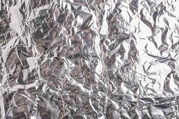 Серебристая скомканная фольга блестящей металлической текстуры, обертывающая бумагу для декоративного элемента обоев. Серый платиновый металлик
 - Фото, изображение