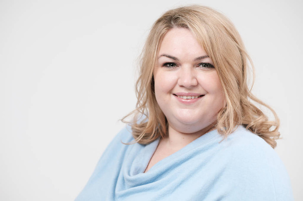 Young obese woman in casual blue clothes on a white background in the studio. Bodypositive. - Фото, зображення